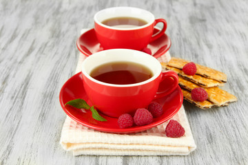 Cups of tea with cookies and raspberries on table close-up