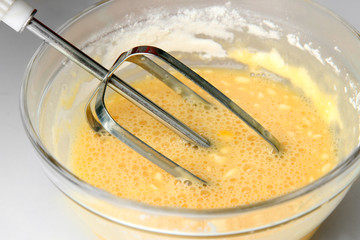 Cooking, whipping eggs with electric whisk in bowl, close up