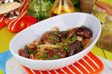 Fried chicken livers in pan on wooden table close-up