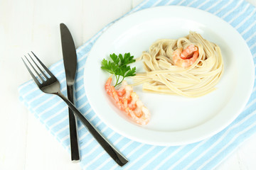 Pasta with shrimps on white plate, on wooden background