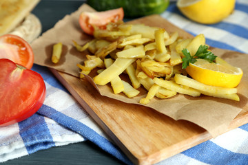 Ruddy fried potatoes on wooden board on table close-up