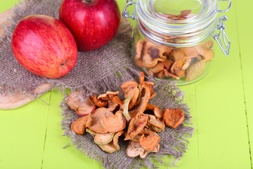 Dried apples in glass jar, on color wooden background