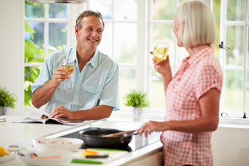 Middle Aged Couple Cooking Meal In Kitchen Together
