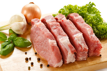 Raw pork on cutting board and vegetables