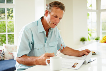 Middle Aged Man Reading Magazine Over Breakfast