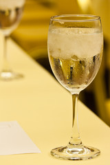 Glass with water and ice with golden color background