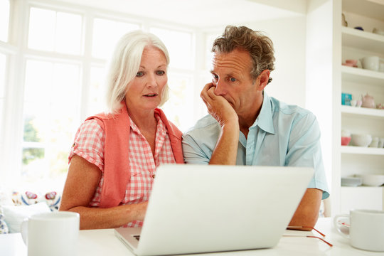 Worried Middle Aged Couple Looking At Laptop