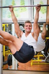 Smiling young man hanging from gym equipment