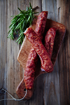 Dried sausage with rosemary on a chopping board