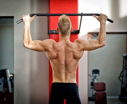 Athletic young man hanging from gym equipment