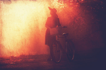 Fototapeta na wymiar Girl on a bike in the countryside in sunrise time.