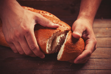 Baker's hands with a bread. Photo with high contrast
