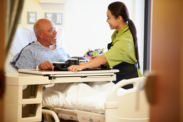 Senior Male Patient Being Served Meal In Hospital Bed