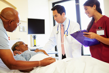 Obraz premium Medical Team Meeting With Senior Couple In Hospital Room