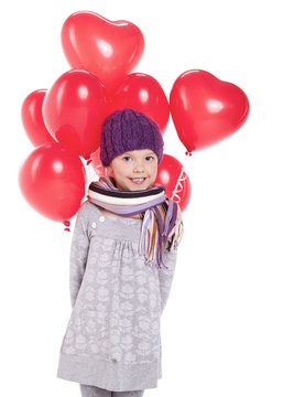 Cute little girl holding a bunch of red heart-shaped balloons