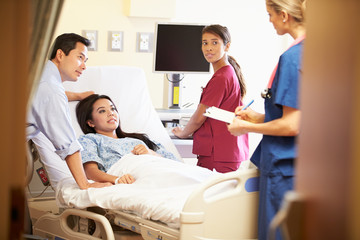 Obraz premium Medical Team Meeting With Couple In Hospital Room