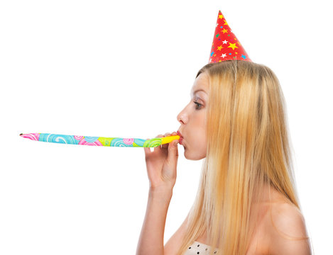 Profile portrait of girl in cap blowing in party horn blower