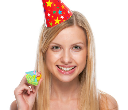 Portrait of smiling teenage girl in cap party horn blower