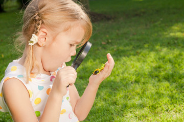 one little girl with magnifying glass outdoors in the day time