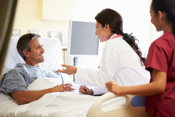 Female Doctor Talking To Male Patient In Hospital Room