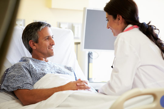 Female Doctor Talking To Male Patient In Hospital Room