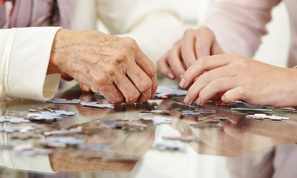 Old hands solving jigsaw puzzle