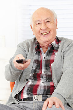 Senior man with remote control watching TV