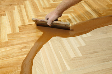 Home renovation varnishing oak parquet floor worker hand, brush