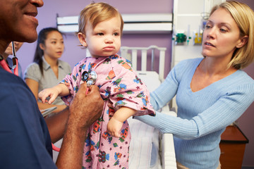 Mother And Daughter With Staff In Pediatric Ward Of Hospital