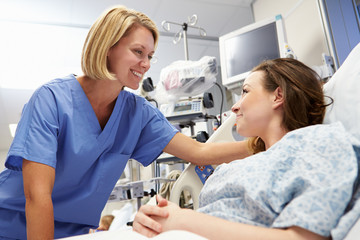 Young Female Patient Talking To Nurse In Emergency Room - obrazy, fototapety, plakaty