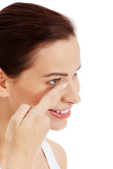 Young beautiful woman putting contact lens.