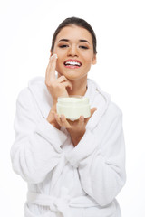 Beautiful woman in bathrobe with face cream.