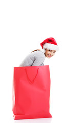 Beautiful girl wearing santa hat in red shopping bag.