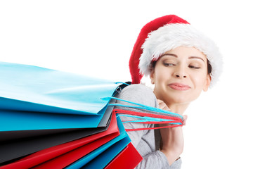 Beautiful woman in santa hat carrying shopping bags.
