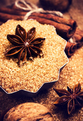 Cinnamon sticks and star anise on cane sugar on wooden backgroun