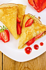 Pancakes with strawberries and jam on a white plate