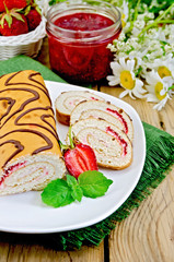 Roulade with strawberries and daisies on a board
