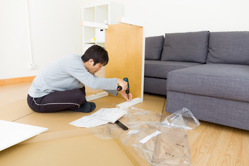 Fototapeta na wymiar Asian man assembling table at living room