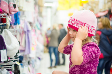 Adorable girl on shoppping cart select clothes in supermarket