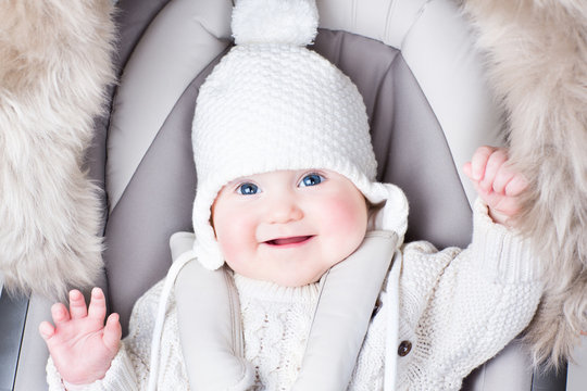 Cute smiling baby sitting in a stroller on a cold winter day