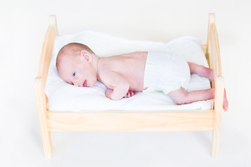 Tiny newborn baby in a toy bed