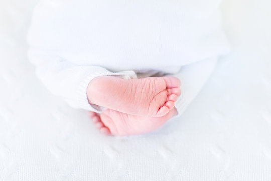 Close up picture of tiny baby feet on a white knitted blanket