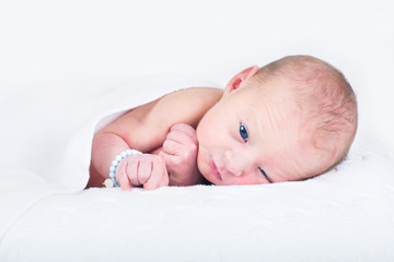 One day old newborn baby relaxing on a knitted white blanket