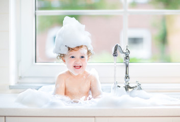 Funny laughing baby girl splashing water playing in a kitchen si