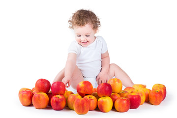 Fototapeta premium Happy laughing baby girl playing with red and yellow apples