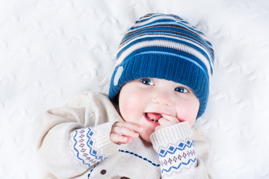 Funny Laughing Baby In A Blue Knitted Hat And A Warm Sweater