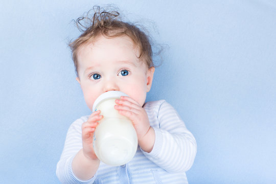 Sweet Little Baby With Blue Eyes Drinking Milk In A Bottle