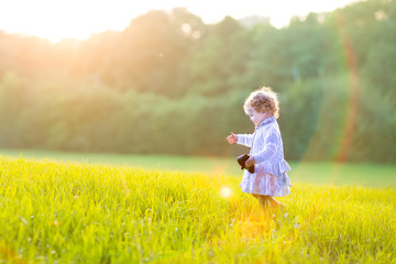 Fototapeta premium Adorable baby girl walking in an autumn field at sunset