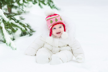 Beautiful laughing baby girl sitting under a Christmas tree