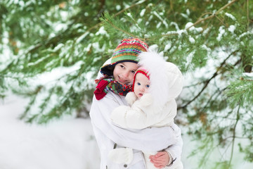 Cute brother and his baby sister wearing white snow jackets